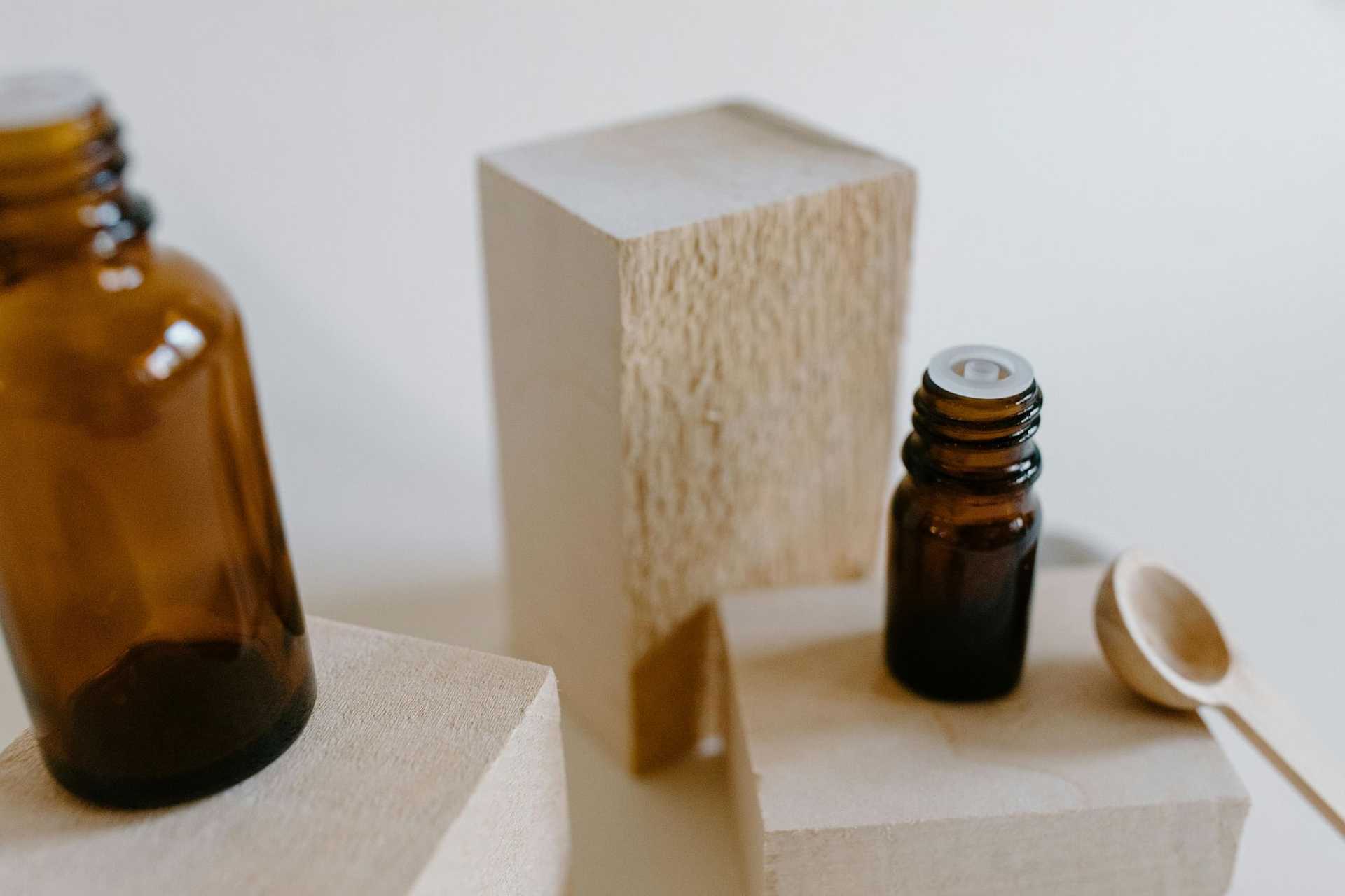 Brown glass bottles on wooden blocks with a wooden spoon, suggesting natural or essential oils.